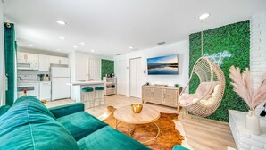 Una sala de estar moderna con un sofá verde, una mesa de centro redonda y una silla colgante.