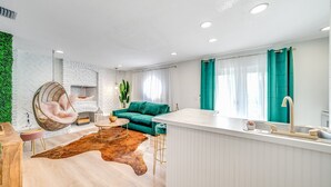 Una sala de estar moderna con un sofá verde, un sillón colgante y una pequeña mesa redonda.