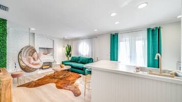 A modern living room with a green sofa, a hanging chair, and a small round table.