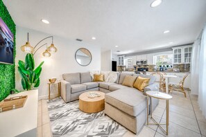 A modern living room with a sectional sofa, a coffee table, and a dining area with chairs.