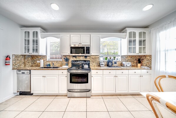 A kitchen with white cabinets, a stainless steel stove, a microwave, and a dishwasher.