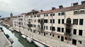 Ein Kanal, gesäumt von historischen Gebäuden, von denen einige Balkone und Schilder mit Informationen über ihre Nutzung aufweisen.