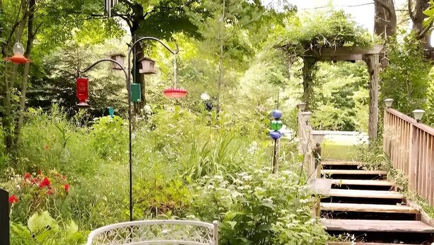Eine Holzterrasse mit einer Metallbank und einer Holztreppe, die nach oben führt.