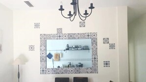 Een eetruimte met een tafel en stoelen, een kroonluchter en een keuken boven de tafel.