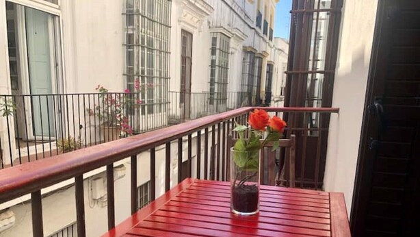 Een rode houten tafel met een bloempot op een balkon.
