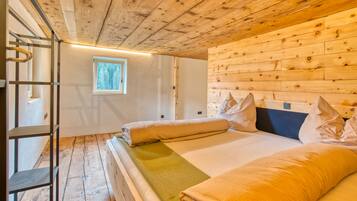 A wooden cabin bedroom with a bunk bed, a window, and a ladder.