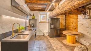 Una cocina moderna con techo de madera, electrodomésticos de acero inoxidable y una mesa redonda de madera.