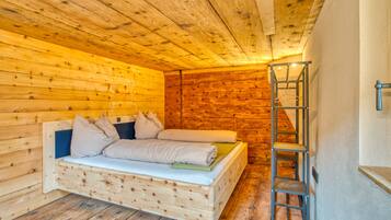 A wooden cabin room with a loft bed and a ladder.