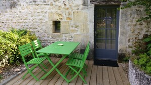 A stone building with a wooden deck, a green table, and matching chairs. - Charming self-catered two story, sleeping four with gated garden and shared pool (Soyaux)