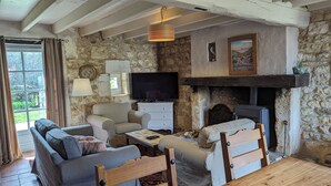 A rustic living room with stone walls, a fireplace, a television, and a sofa. - Charming self-catered two story, sleeping four with gated garden and shared pool (Soyaux)