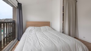 Un dormitorio con un ventanal grande, cabecera de madera y vistas al exterior.