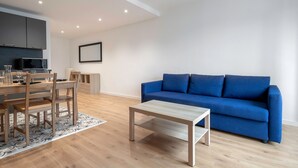 Una sala de estar moderna con un sofá azul, una mesa de comedor de madera y sillas.