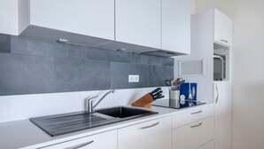 A modern kitchen with a stainless steel sink, white cabinets, a built-in microwave, and a grey tiled backsplash. - Seafront apartment balcony in La Baule - 6 guests (La Baule-Escoublac)