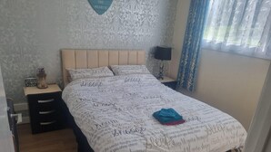 Una camera da letto con un letto, un comodino, una lampada e una sveglia a muro.