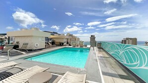 A rooftop pool area with lounge chairs and a view of the ocean. - Renovated Waikiki Studio! City View, Full Kitchen, Free Wi-Fi & Parking, Pool (Honolulu)