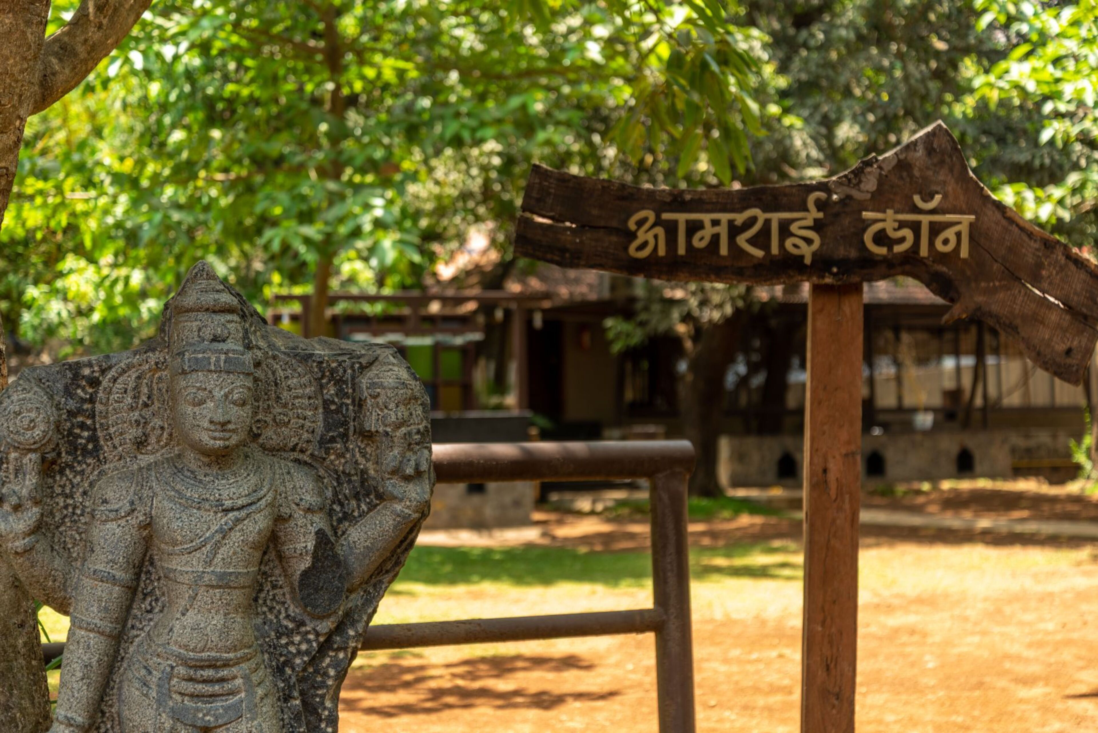 A stone statue of a deity with a sign in the background.