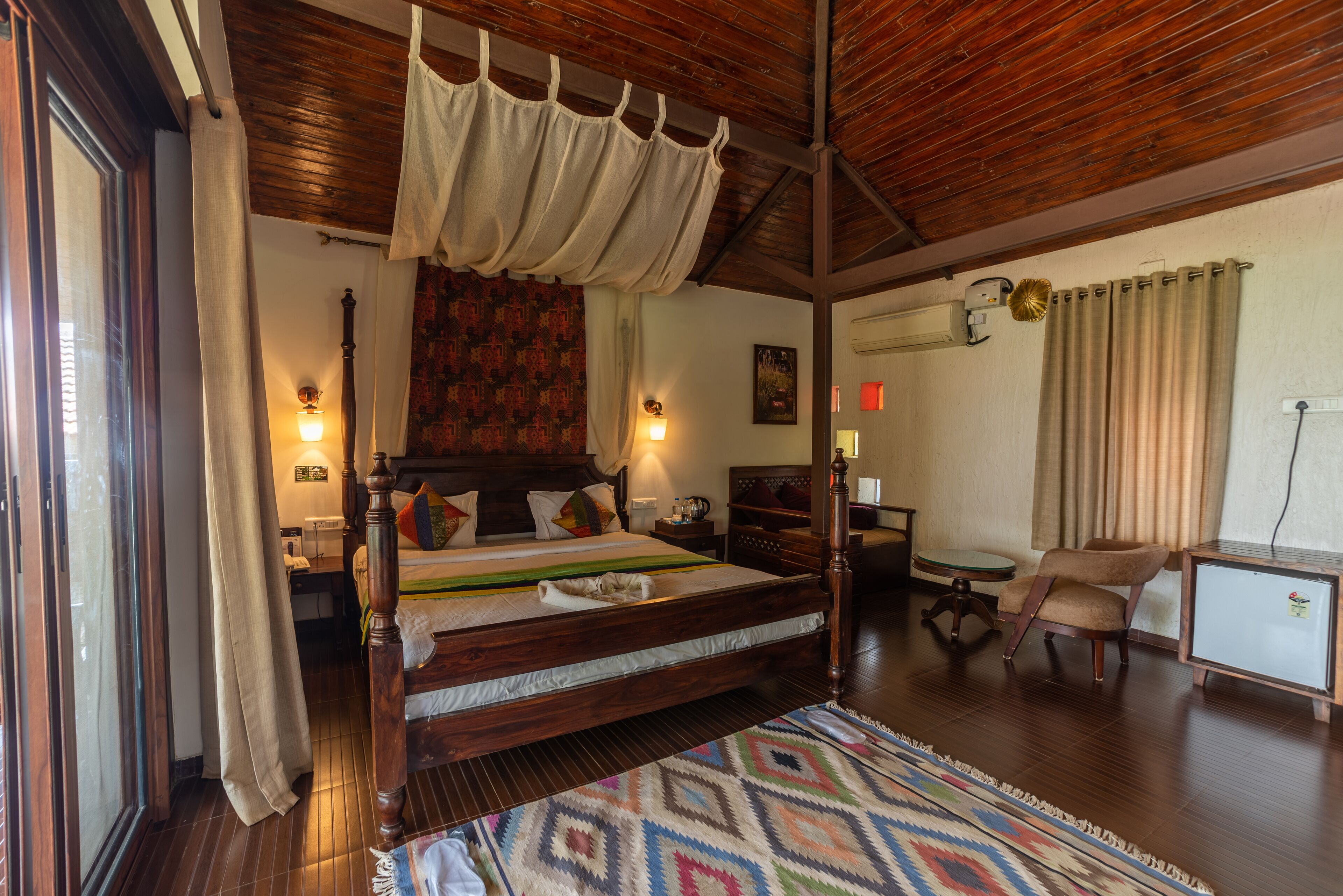 Une chambre spacieuse avec un grand lit, un plafond en bois, un petit bureau, une chaise et une table de chevet.
