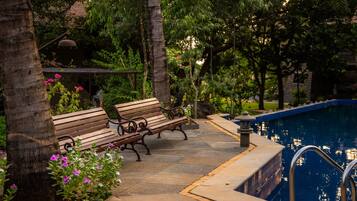 A poolside area with wooden benches and a stone pathway.
