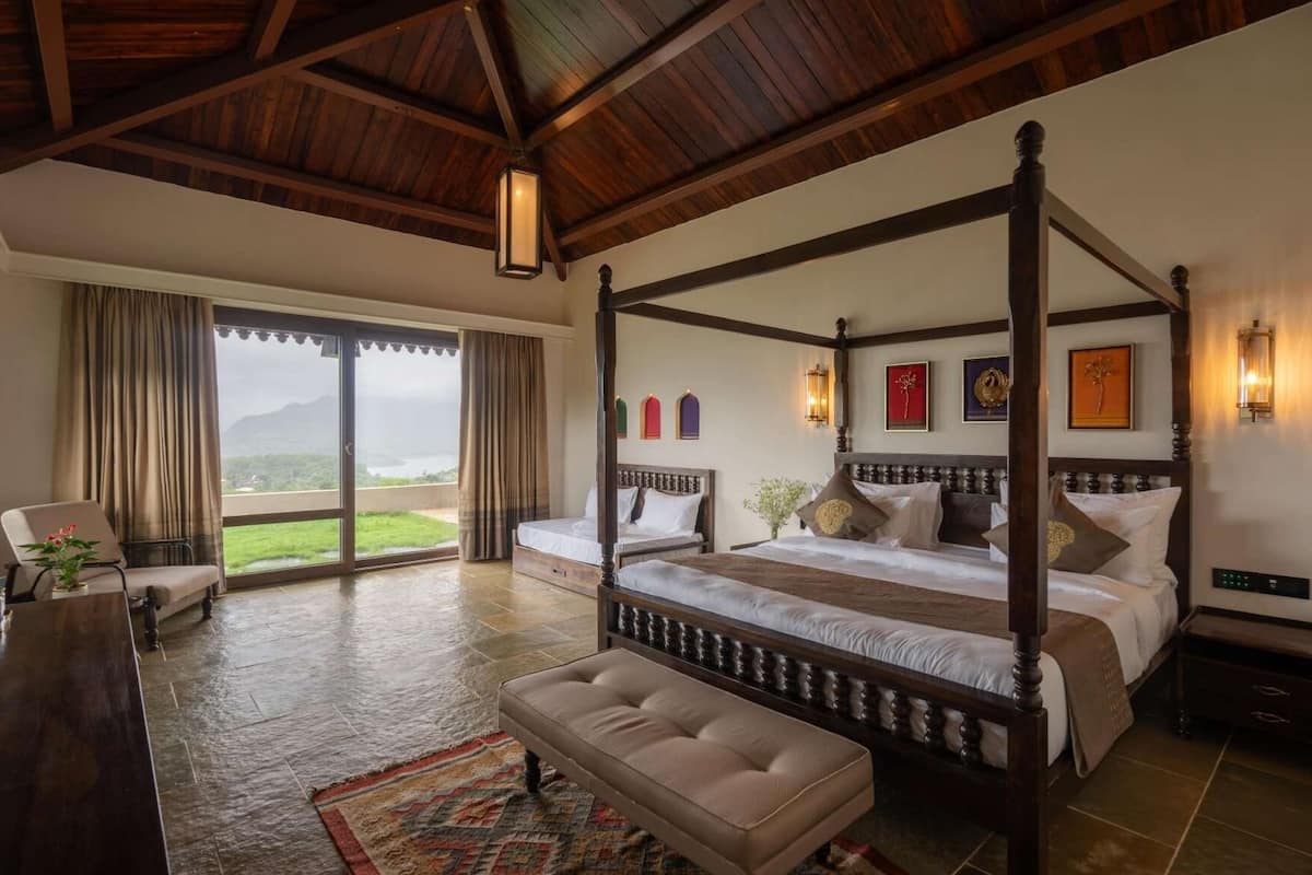 A four-poster bed with a view of a green landscape through a sliding door.