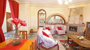 A cozy living room with a fireplace, two armchairs, a sofa, and a dining table with a vase of flowers. - A captivating retreat with pool for an exceptional group holiday. Pet friendly. (Comares)