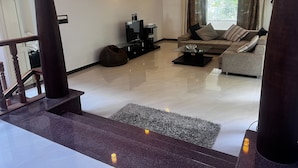 A modern living room with a sofa, a coffee table, and a TV. There is a staircase leading to another level. - Yercaud Bungalow Stay (Yercaud)