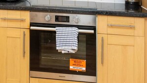 Una cocina con armarios de madera, una campana extractora de acero inoxidable, un microondas, un horno y una cafetera sobre la encimera.