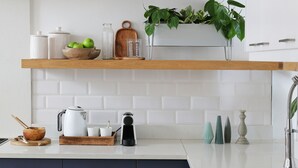 Una cocina moderna con estantes de madera, baldosas blancas y armarios azules.