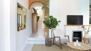 Una sala de estar moderna con un arco de piedra, una escalera, un televisor de pantalla plana, una chimenea y un comedor.