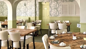 Un comedor con mesas redondas, sillas blancas y papel tapiz floral.