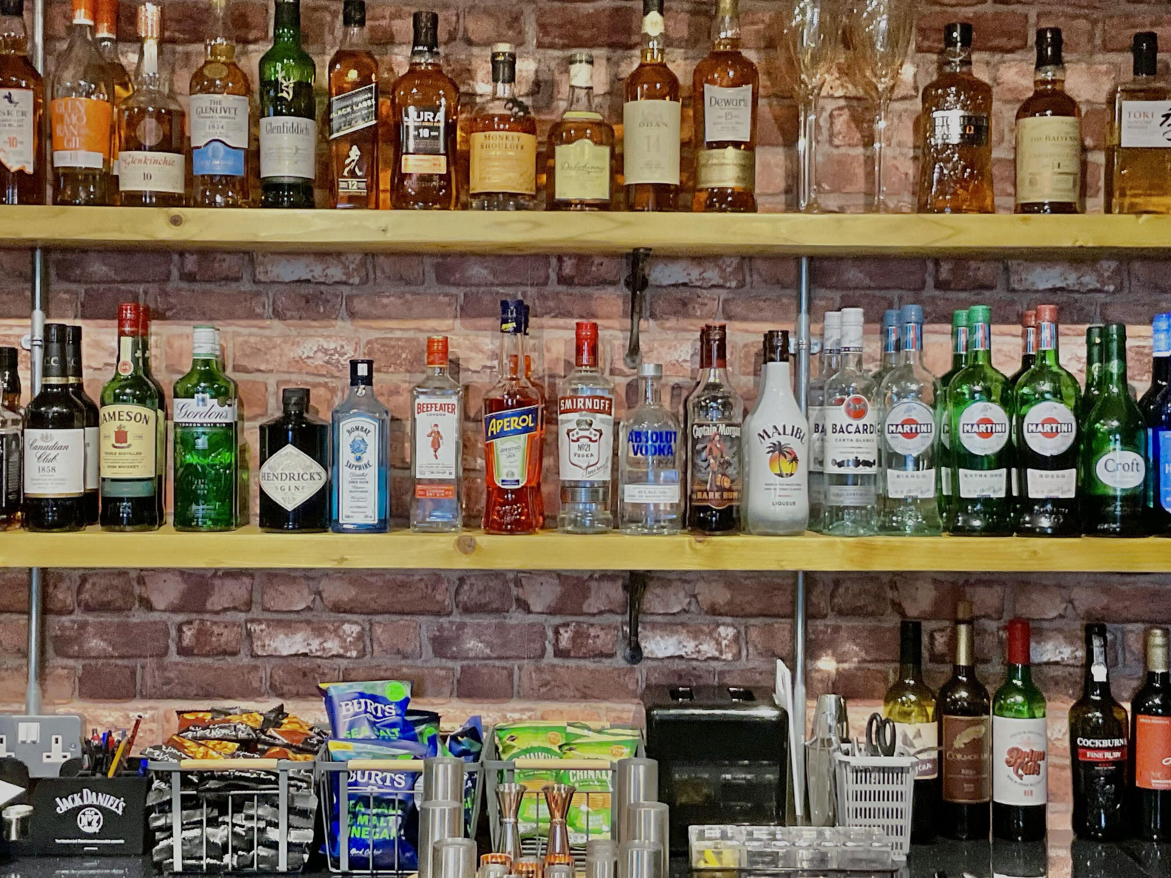 Shelves stocked with various liquor bottles, a coffee machine, and snack packets.
