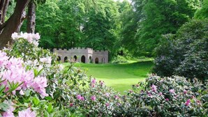 Una estructura al estilo de castillo rodeada de exuberante follaje y plantas florecientes.