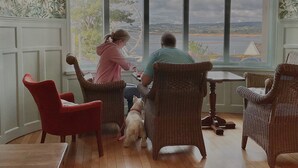 Una habitación con ventanas amplias, mobiliario de mimbre y vista a un cuerpo de agua.