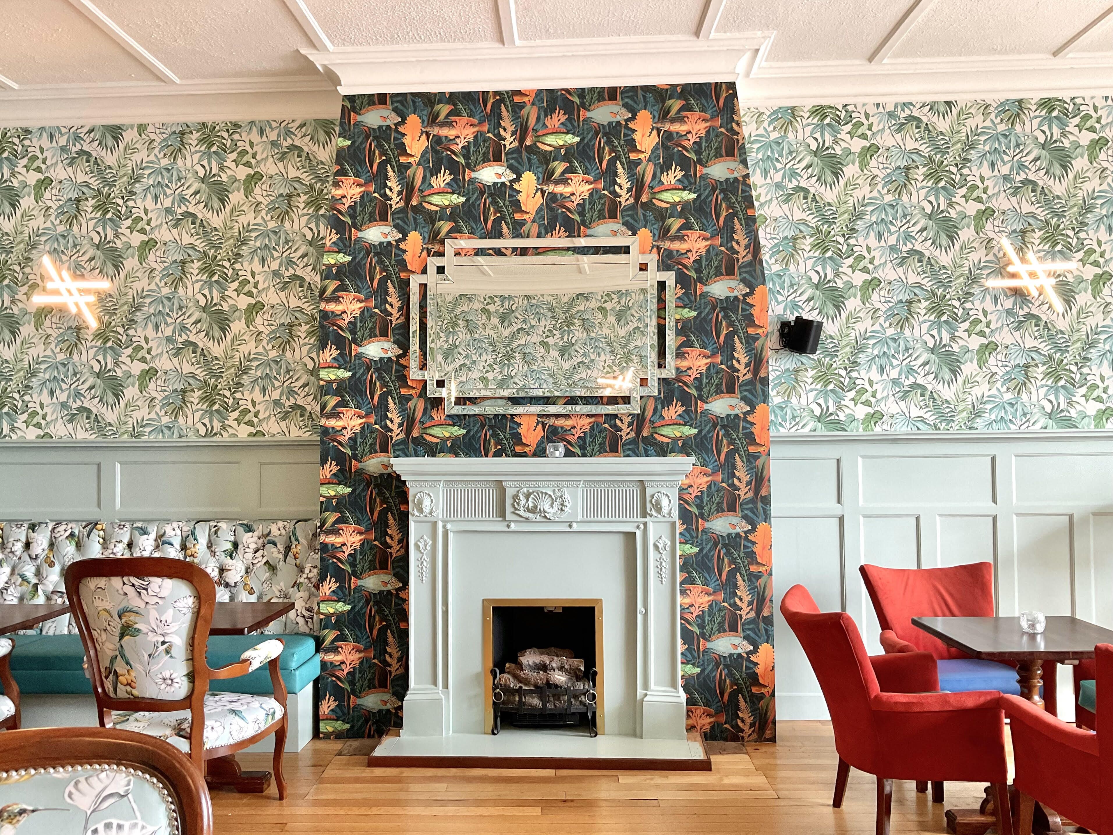 Una habitación con chimenea, papel tapiz estampado y muebles de madera.