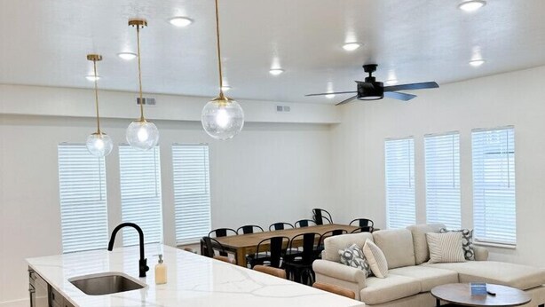 Une cuisine moderne dotée d’un grand îlot central, d’un coin repas avec un canapé et d’un ventilateur de plafond.