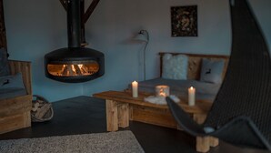 A cozy living room with a wood-burning stove, a sofa, a coffee table, and a chair.