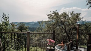 A wooden deck with a hot tub, a white furry rug, and a flower pot.