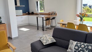 A modern living room with a grey sofa, yellow armchair, and a dining area with a table and chairs. - The iodine parenthesis. House with garden - Near sea (Plozévet)