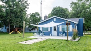 Une maison bleue avec un patio, une balançoire et un auvent blanc.