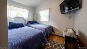 Une chambre avec deux lits, un téléviseur à écran plat et une fenêtre avec des rideaux.