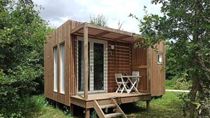 A wooden cabin with a deck, a table, and chairs.