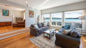 Un salon spacieux doté d’une grande fenêtre donnant sur un lac, et aménagé avec des canapés et une table basse.