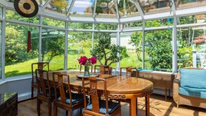 Une véranda avec une table à manger en bois, des chaises et un canapé en osier.