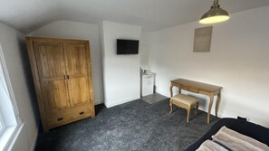 Cozy retreat with a large wardrobe, flat-screen TV, and comfortable seating area.