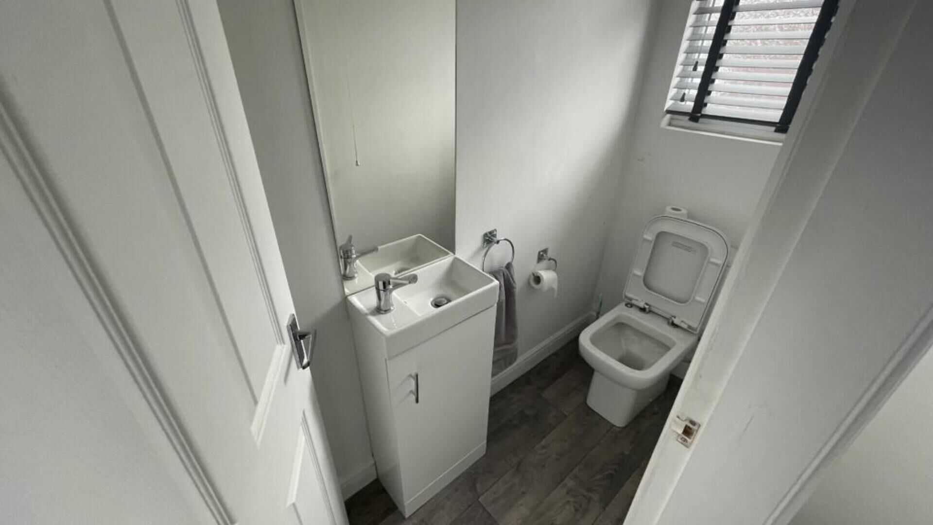 A small, compact bathroom with a white sink, a toilet, and a mirror.