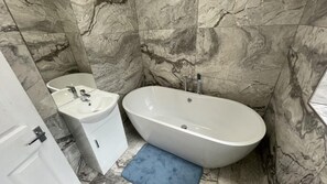 A bathroom with a freestanding bathtub, a sink, and a cabinet.