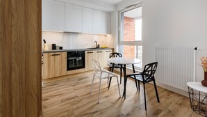 Eine moderne Küche mit weißen Schränken, einer Holzarbeitsplatte und einem Essbereich mit zwei Stühlen und einem kleinen Tisch.