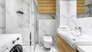 Ein modernes Badezimmer mit Duschkabine aus Glas, Toilette und Waschbecken mit Holzschrank.