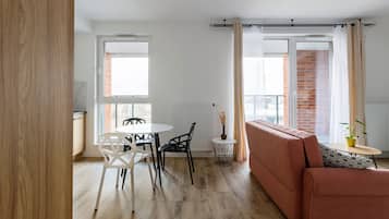 A modern living room with a sofa, a dining table with chairs, and a small side table with a plant.
