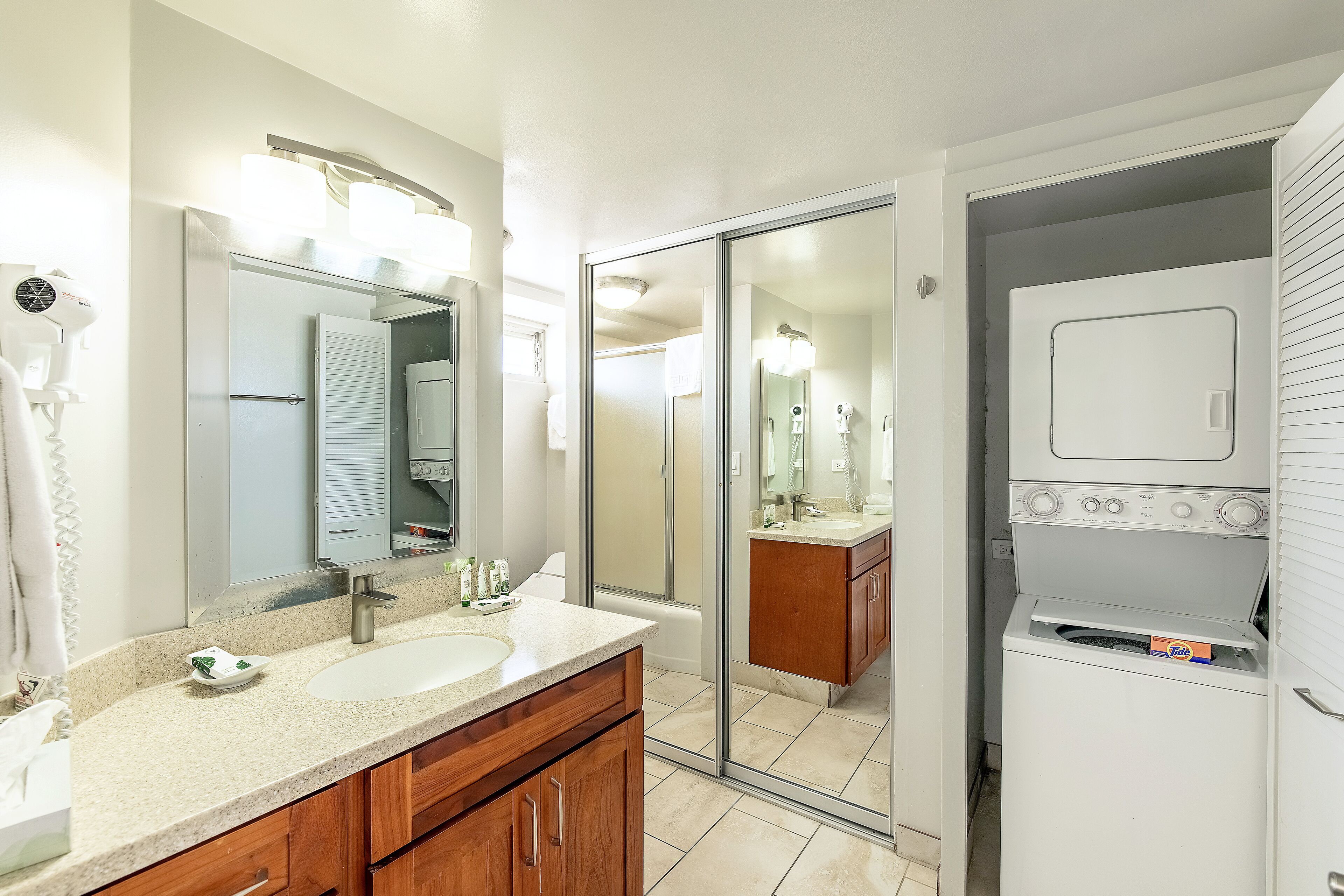 A bathroom with a sink, mirror, and a built-in washing machine.