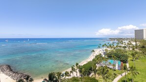 A coastal resort with a clear view of the ocean, a sandy beach, and a pool area surrounded by palm trees. - Oceanfront Studio | Spectacular Views | Full Kitchen | Nearby Parking(Fee) (Honolulu)